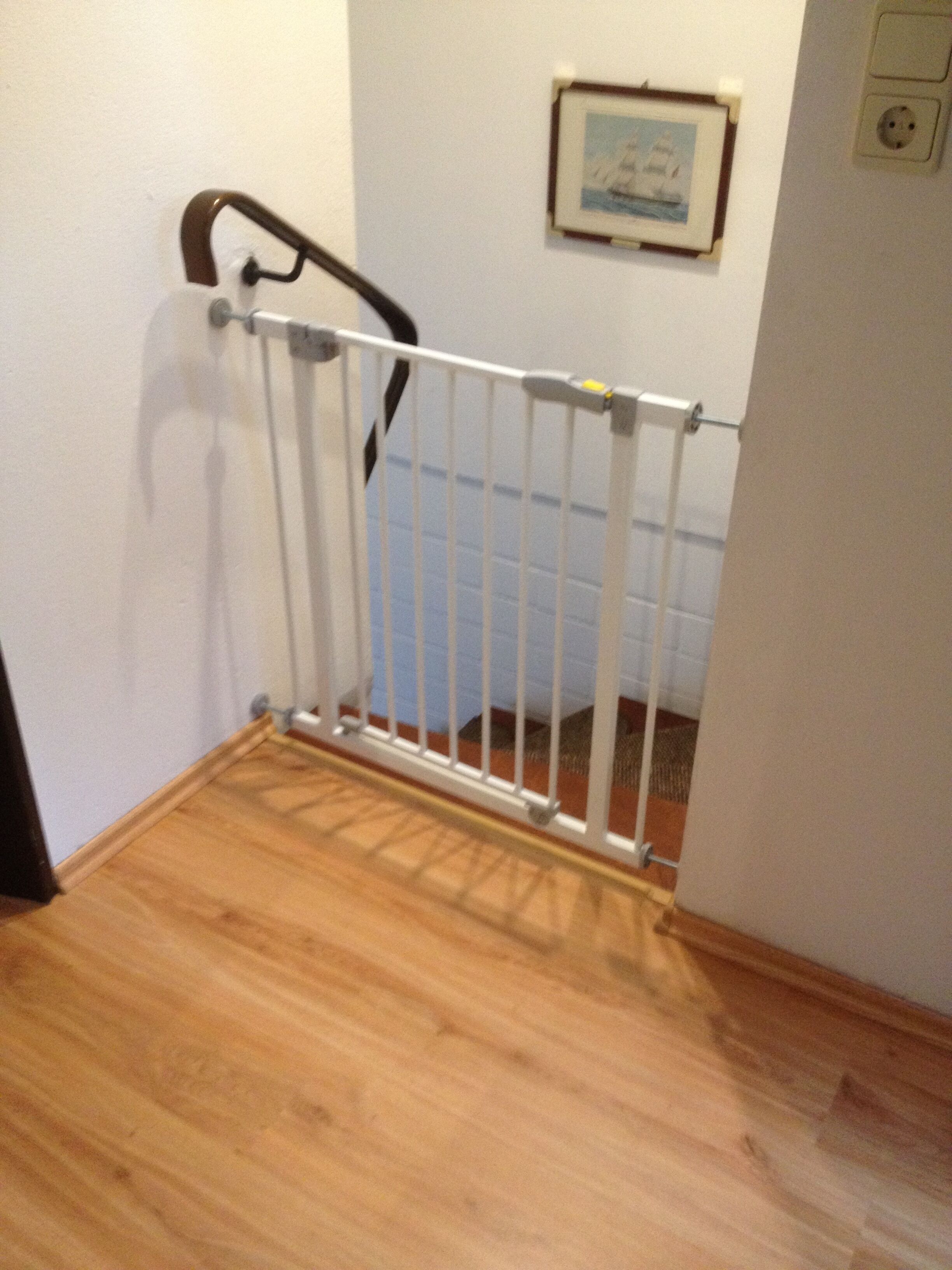 A wooden staircase with a white safety gate at the top.