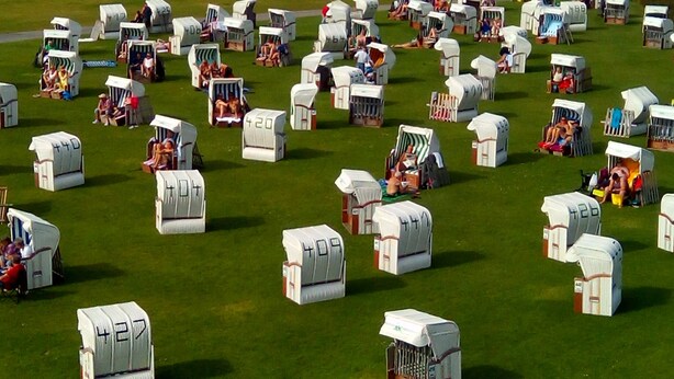 A campsite with numerous numbered tents and a wooden chair with a sign in the foreground.
