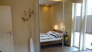Une chambre à coucher avec un lit, une table de chevet et un meuble avec miroir.