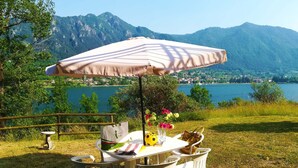 Un espace extérieur aménagé pour les repas, avec une table et des chaises, une table de pique-nique et un grand parasol.