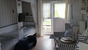 Ein Zimmer mit Etagenbetten, einem Schreibtisch mit Computer, einem Stuhl und einem kleinen Tisch mit Laterne.