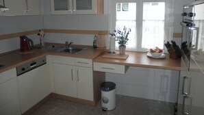 A modern kitchen with white cabinets, a wooden countertop, a sink, a stove, and a window with blinds. - Exclusive apartment (3 rooms, 85 sqm) in a quiet location, only 50m to the beach! (Heringsdorf)