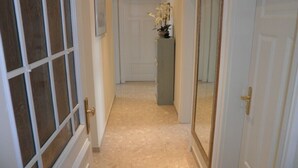A hallway with a tiled floor, white doors, and a vase with flowers on a pedestal. - Exclusive apartment (3 rooms, 85 sqm) in a quiet location, only 50m to the beach! (Heringsdorf)