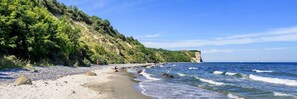 Una playa con piedras, un acantilado y el océano.