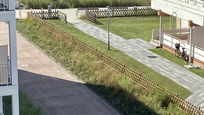 A coastal view with a pathway leading to a building with a balcony overlooking the sea.
