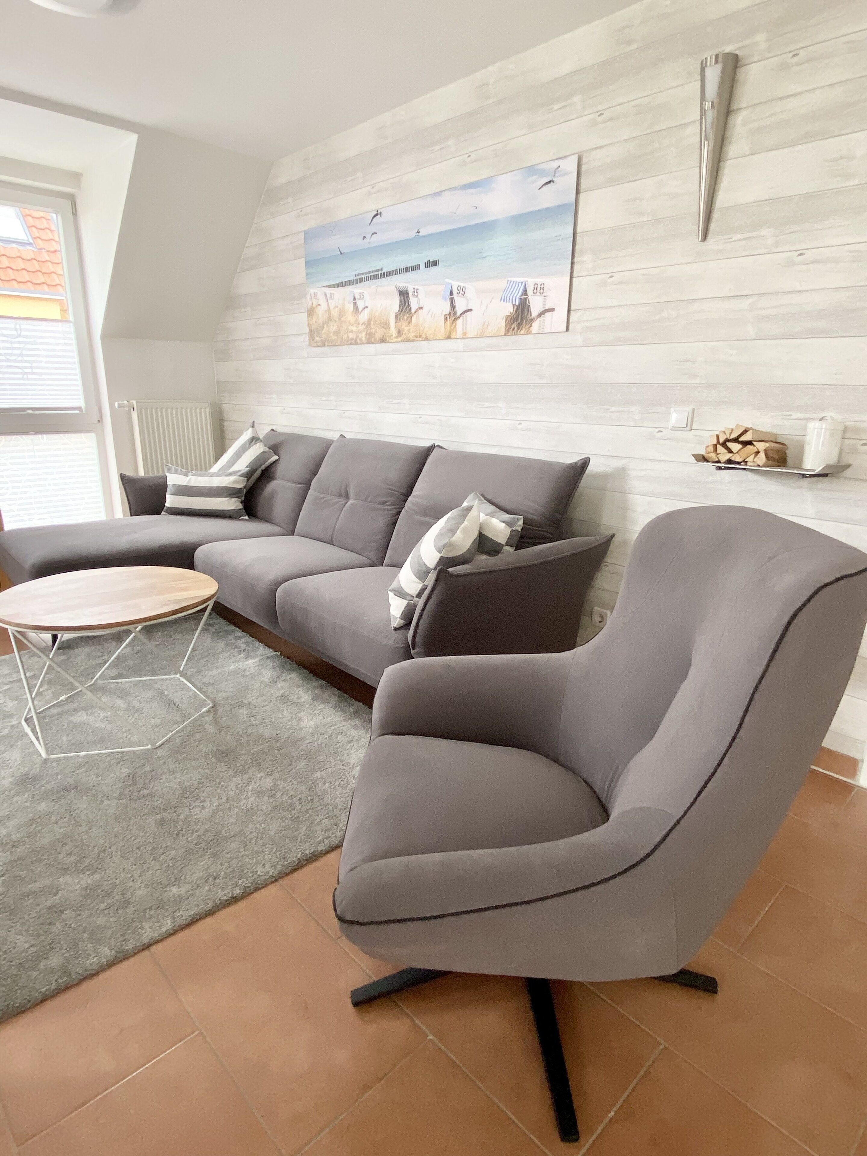 A modern living room with a grey sectional sofa, a round coffee table, and a grey armchair.