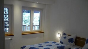 Ein Schlafzimmer mit zwei Betten, einem Fenster mit Blick, einem Heizkörper und einer Wandleuchte.