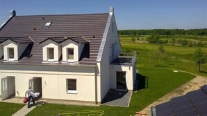 Een modern huis met een schuin dak, meerdere dakramen en een klein balkon.