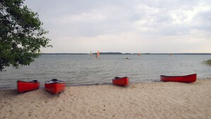 Een zandstrand met daaraan een rij rode kano's.