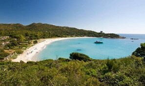 A coastal landscape with a sandy beach, clear blue waters, and a boat. - +++ Cozy holiday home with sea view +++ (Costa Rei)