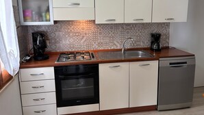 Una cucina compatta con piano cottura a gas, forno, lavastoviglie e macchina da caffè.