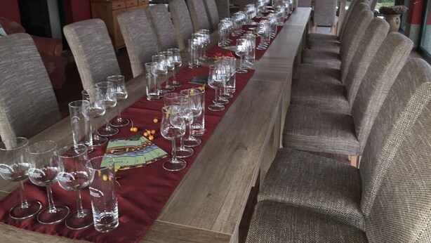 A long dining table set with multiple wine glasses and a red table runner, surrounded by upholstered chairs.