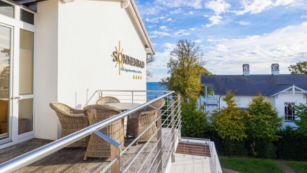 Ein Hotelbalkon mit Korbmöbeln, einem Metallgeländer und Blick auf das Meer.
