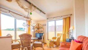 Ein Wohnzimmer mit Rattanmöbeln, einem Fernseher und einer Couch.