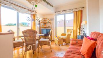 Ein Wohnzimmer mit Rattanmöbeln, einem Fernseher und einer Couch.