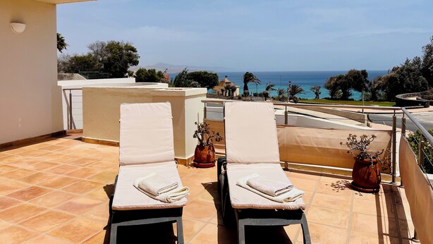 A terrace with two sun loungers, a potted plant, and a view of the sea. - Villa Bali, private pool, fiber-optic internet, ocean view, courtyard, privacy (Costa Calma)