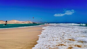 A beach with clear skies, waves, and people windsurfing. - Villa Bali, private pool, fiber-optic internet, ocean view, courtyard, privacy (Costa Calma)