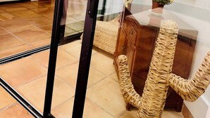 A modern living room with a glass door leading to a balcony, a wicker chair, and a small table with a flower vase. - Villa Bali, private pool, fiber-optic internet, ocean view, courtyard, privacy (Costa Calma)