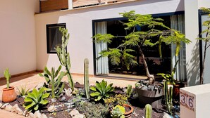 A two-story building with a balcony and a garden with various plants and a cactus. - Villa Bali, private pool, fiber-optic internet, ocean view, courtyard, privacy (Costa Calma)