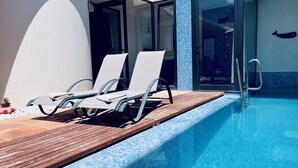 A swimming pool with two white lounge chairs and a wooden deck. - Villa Bali, private pool, fiber-optic internet, ocean view, courtyard, privacy (Costa Calma)