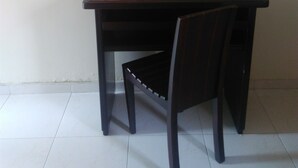 A small, dark wooden desk with a chair, a flat-screen TV mounted on the wall above, and a white tiled floor. - Hotel La Via (Cartagena)