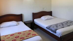 Two single beds with wooden headboards, a nightstand, a wall-mounted lamp, and an air conditioning unit. - Hotel La Via (Cartagena)