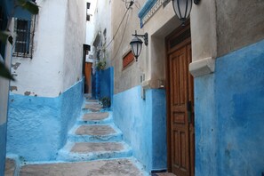 A narrow alleyway with blue-painted walls and a wooden door. - Sultana Larache (Larache)