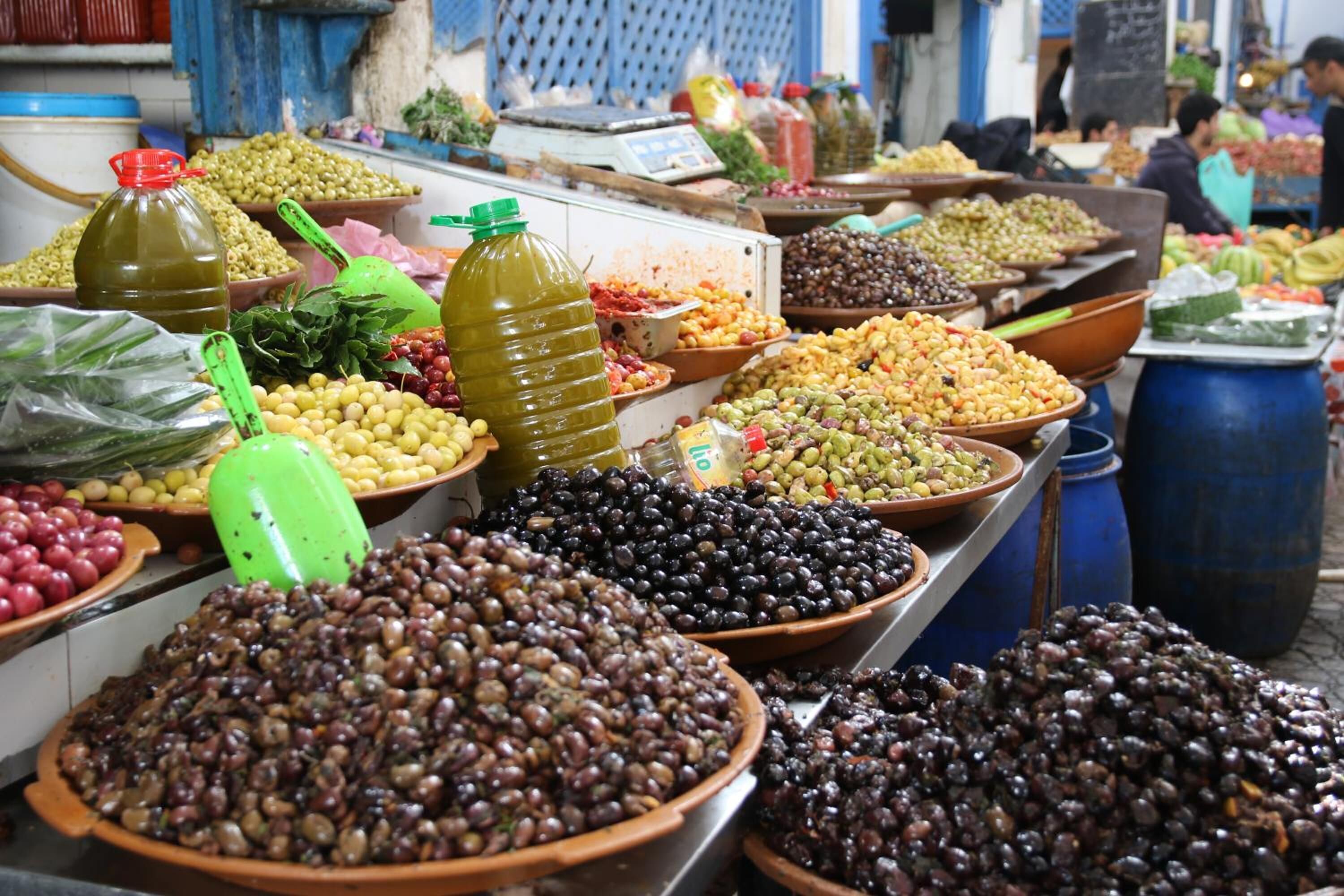 A market stall with various olives and pickles displayed in large bowls and containers.