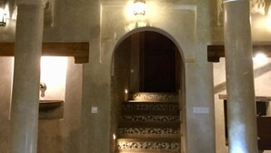 A grand staircase with ornate columns and a decorative archway, leading to an upper level with a balcony.
