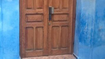Una puerta doble de madera con un picaporte de metal, flanqueada por dos faroles de pared.