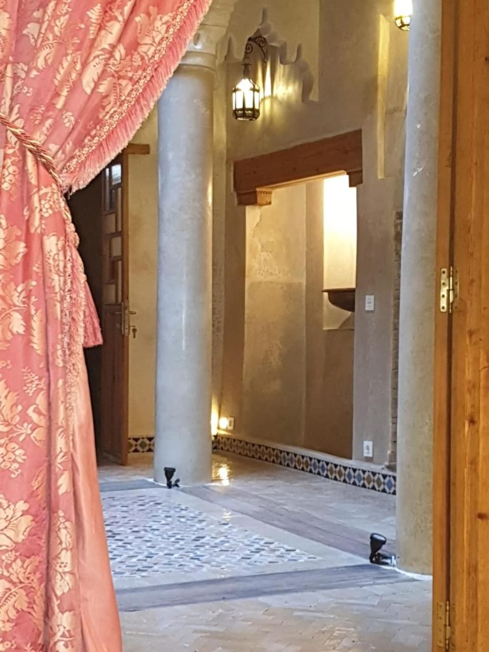 A hallway with columns, a patterned carpet, and a door with a curtain.