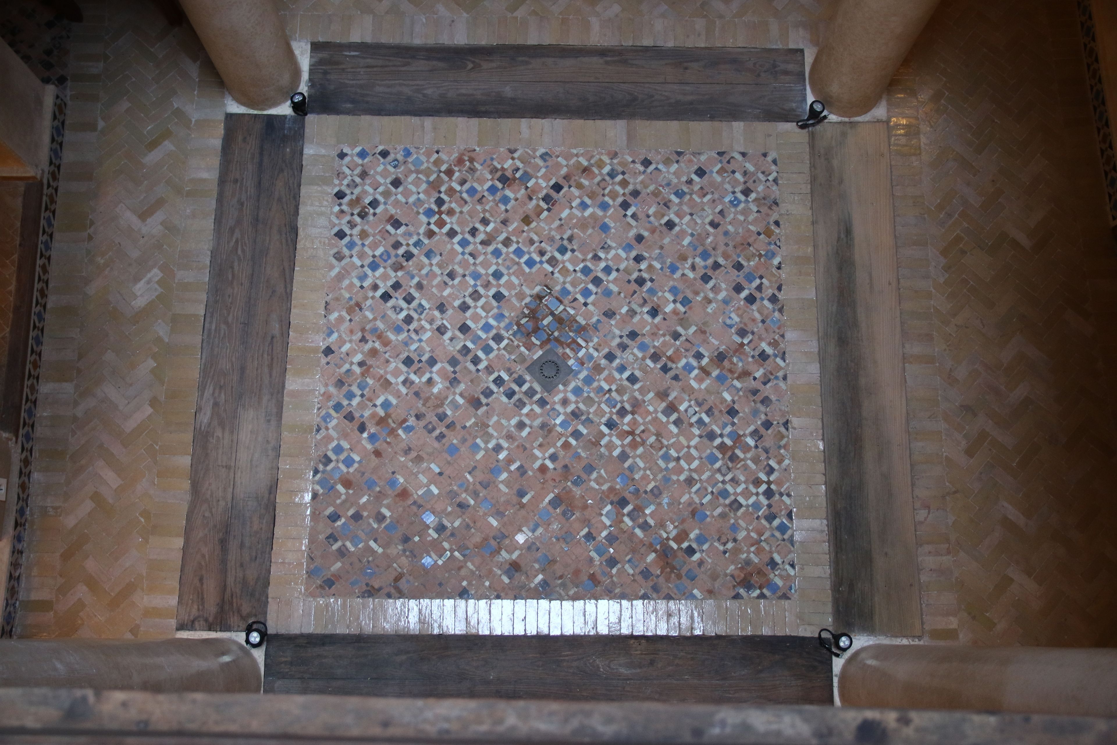 A square tiled floor with a diamond pattern and wooden beams.