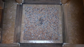 A square tiled floor with a diamond pattern and wooden beams.
