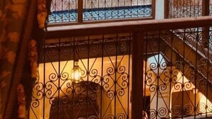 A staircase with ornate metal railings, a white column, and a patterned curtain.