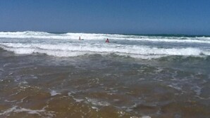 A beach with waves and a clear sky.