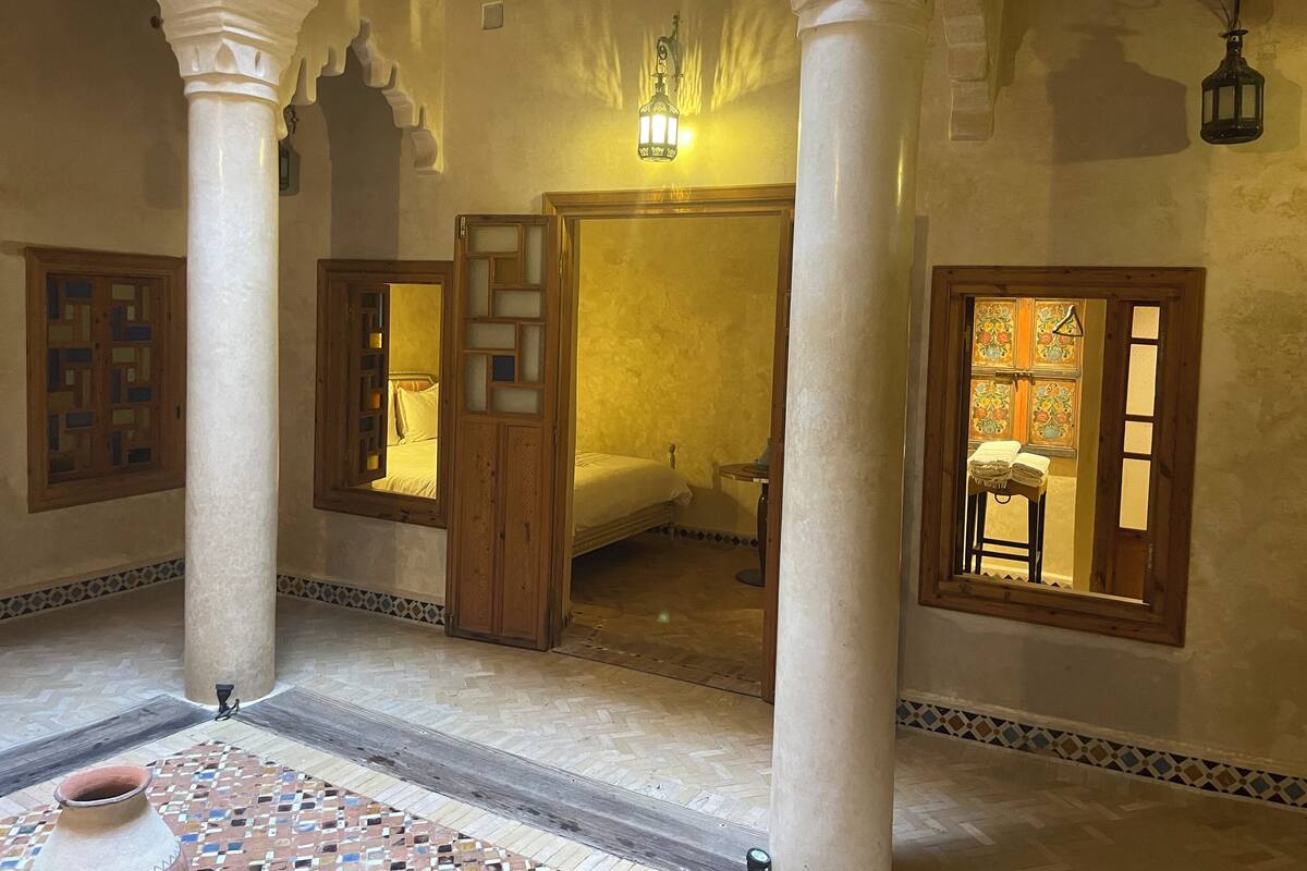 A traditional room with a bed, wooden door with glass panels, and a patterned floor.
