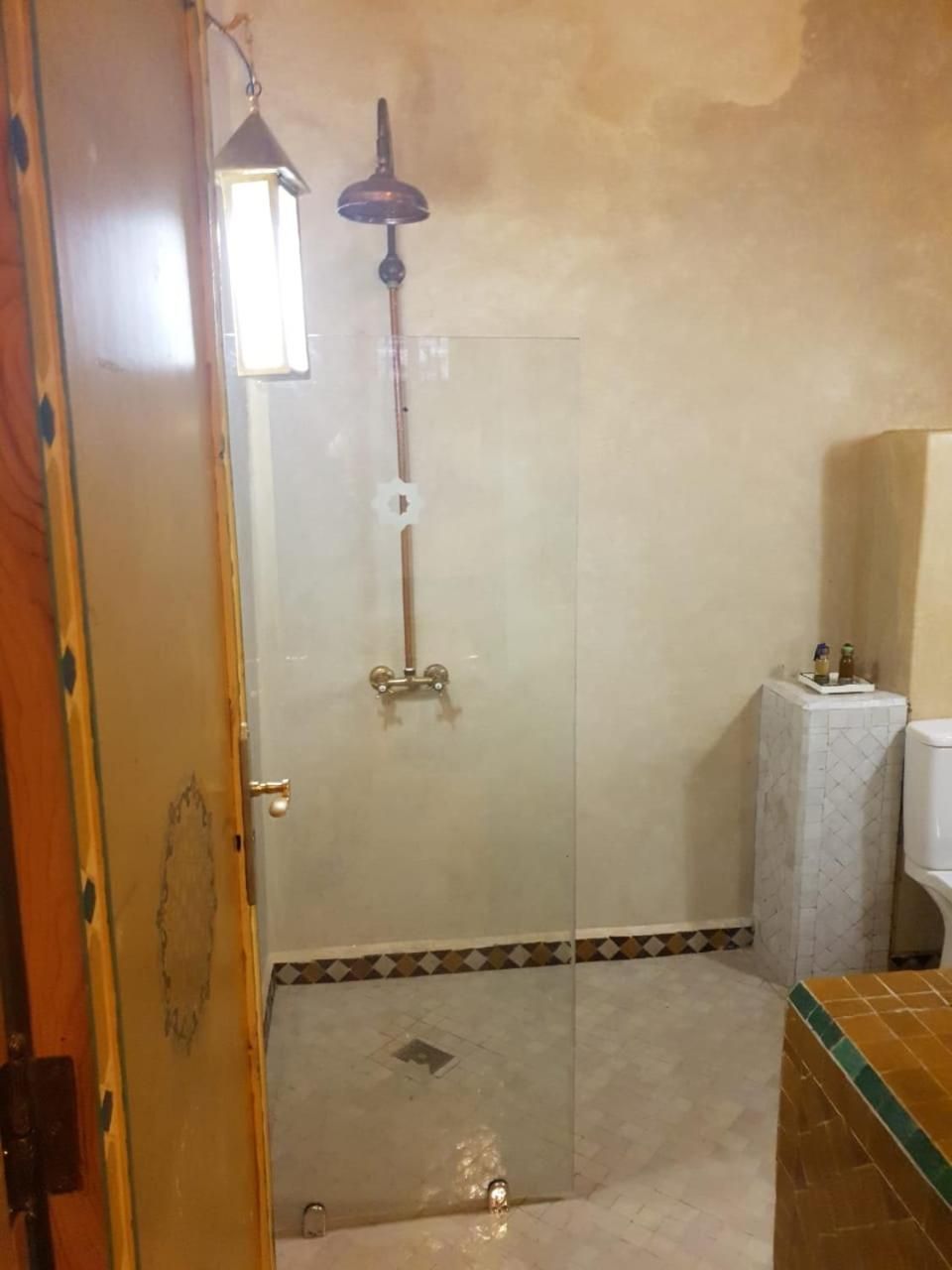 A bathroom with a glass shower enclosure, a toilet, and a sink.