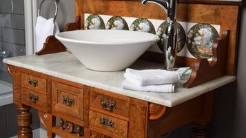 A bathroom with a wooden vanity, a large white basin, and a single silver faucet.