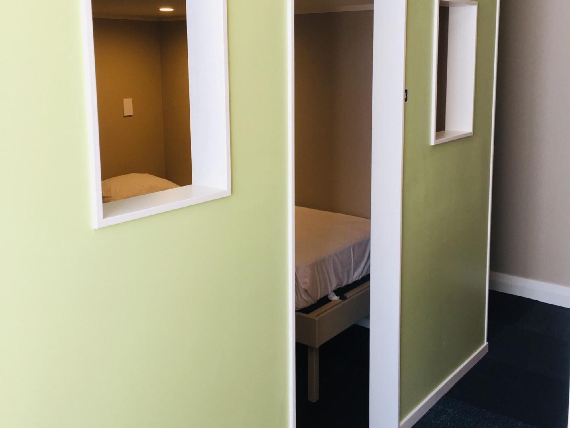Un pasillo con dos habitaciones, cada una con ventana y cama.