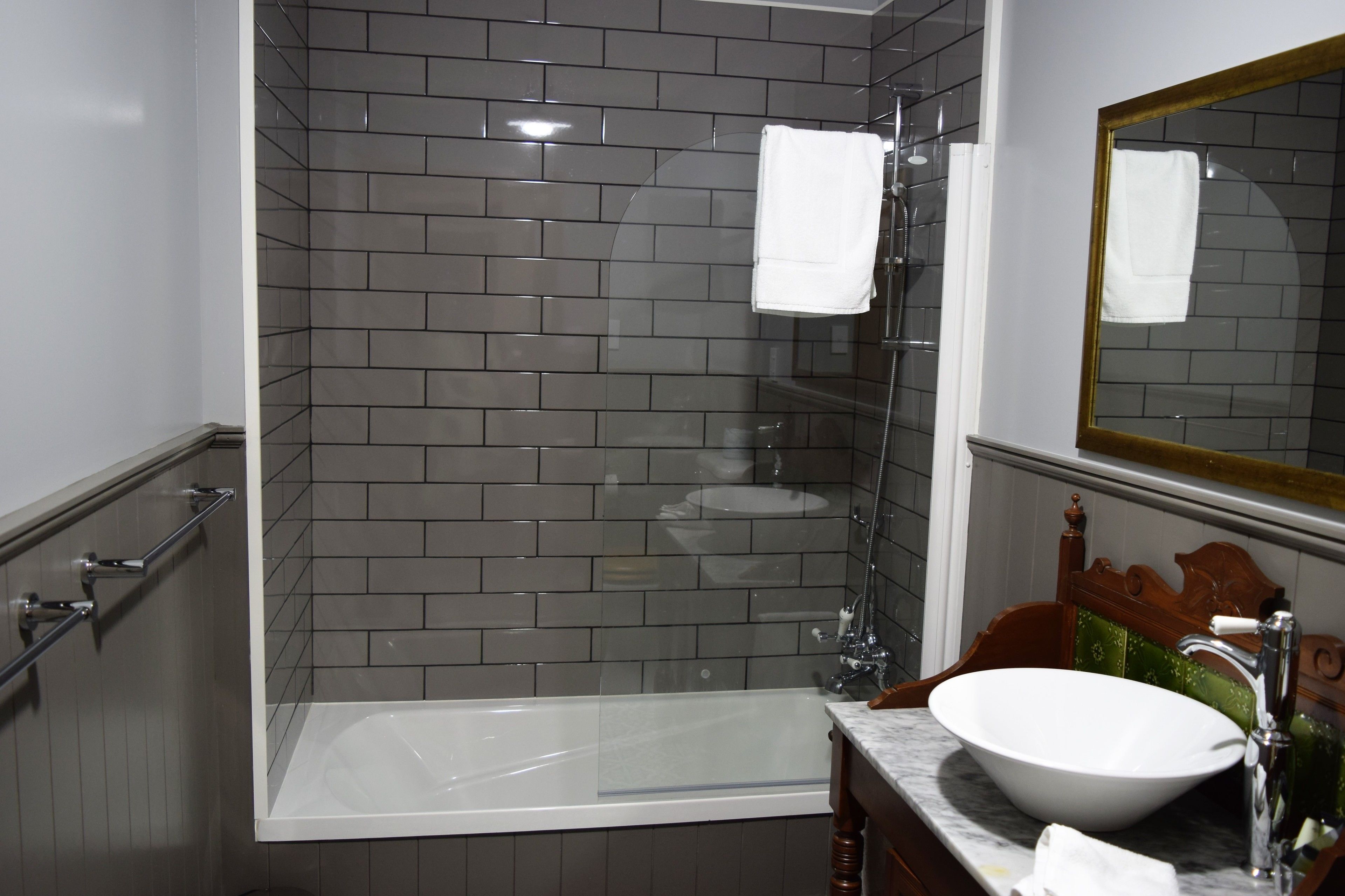 A modern bathroom with a glass-enclosed shower, a white bathtub, and a marble vanity with a sink.