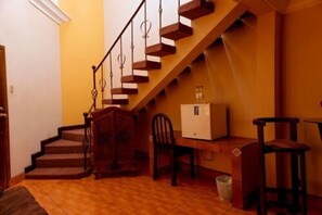 A staircase with wooden steps and metal railings, a wooden desk with a chair, and a trash bin. - Hotel Del Sol (Jutiapa)