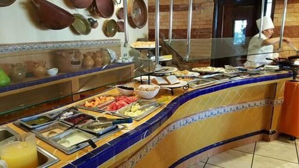Un buffet con diversi cibi e uno chef sullo sfondo.
