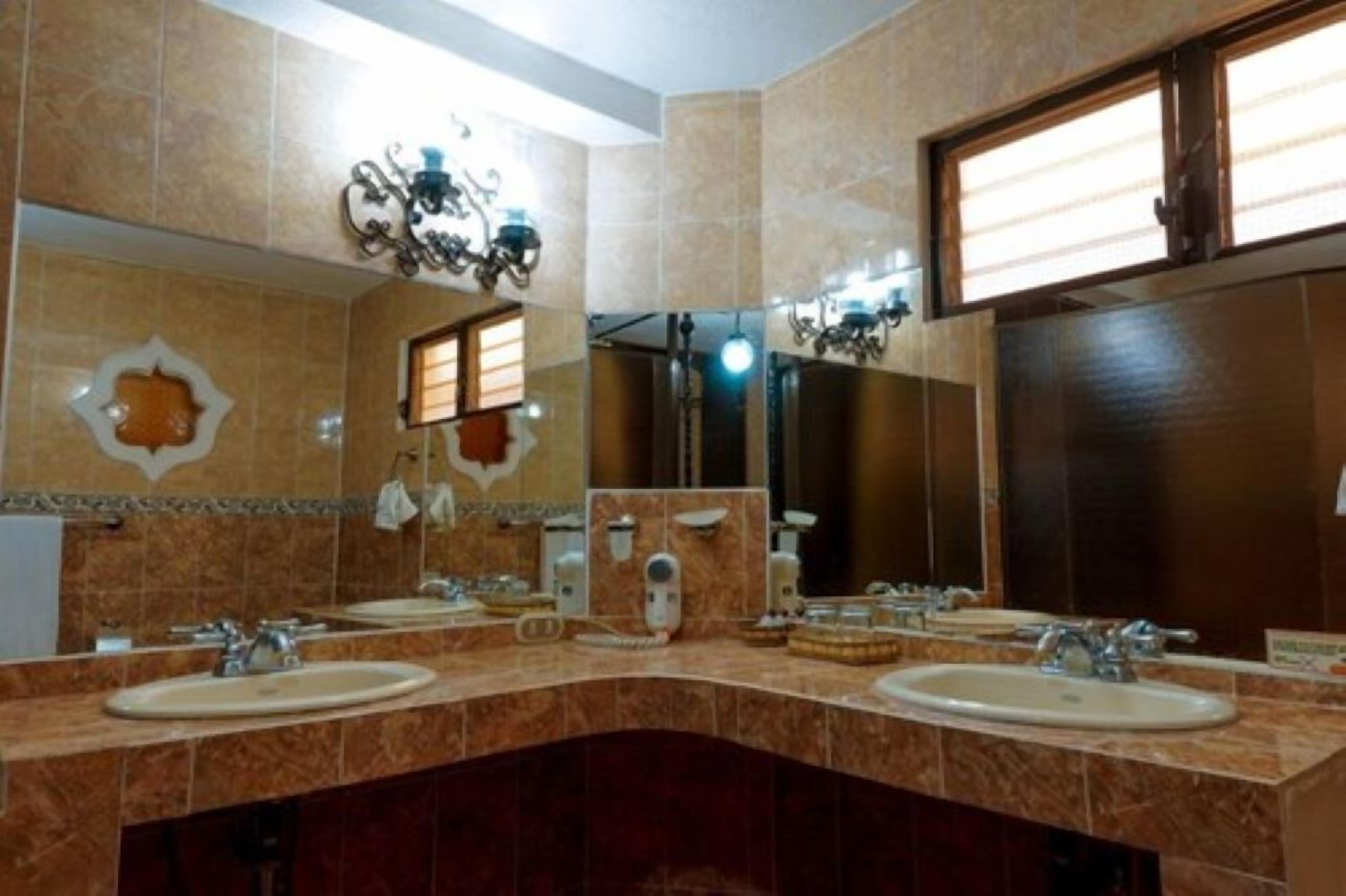Un baño con dos lavamanos, un espejo y una ducha.
