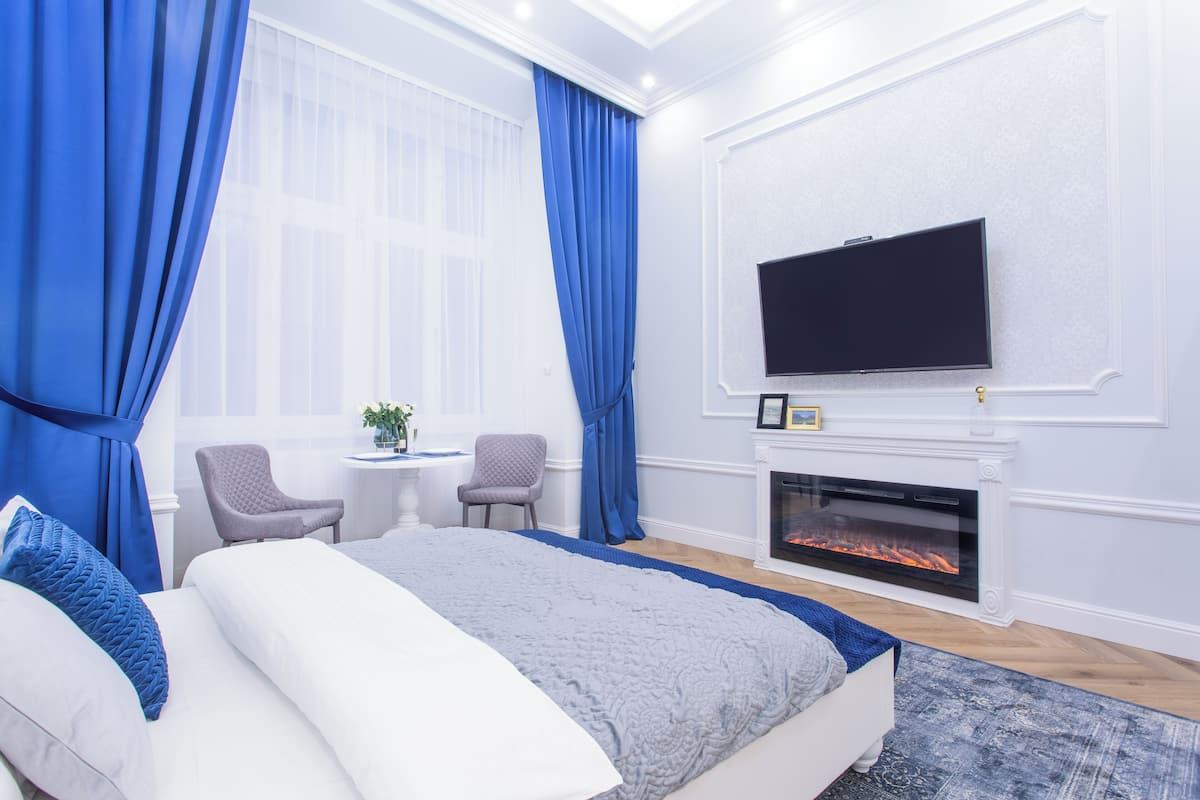 Un dormitorio con una cama, chimenea, televisor y dos sillones.