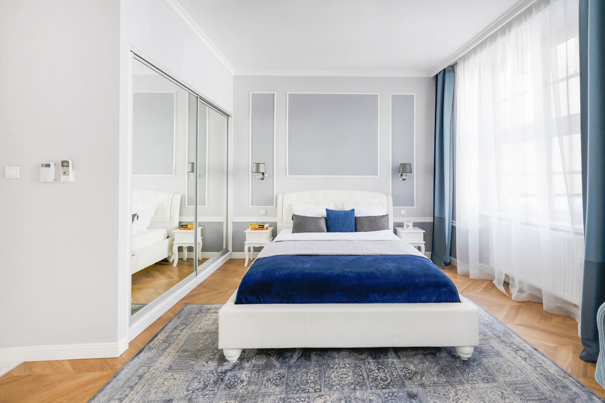 Un dormitorio moderno con una cama grande, un espejo, una mesita de noche y una mesilla.