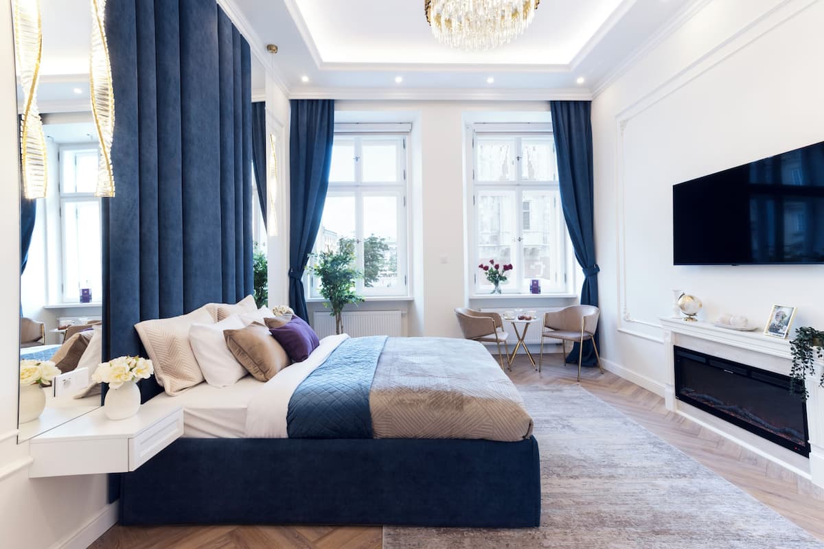 Un dormitorio moderno con una cama grande, televisor, chimenea y zona de comedor.