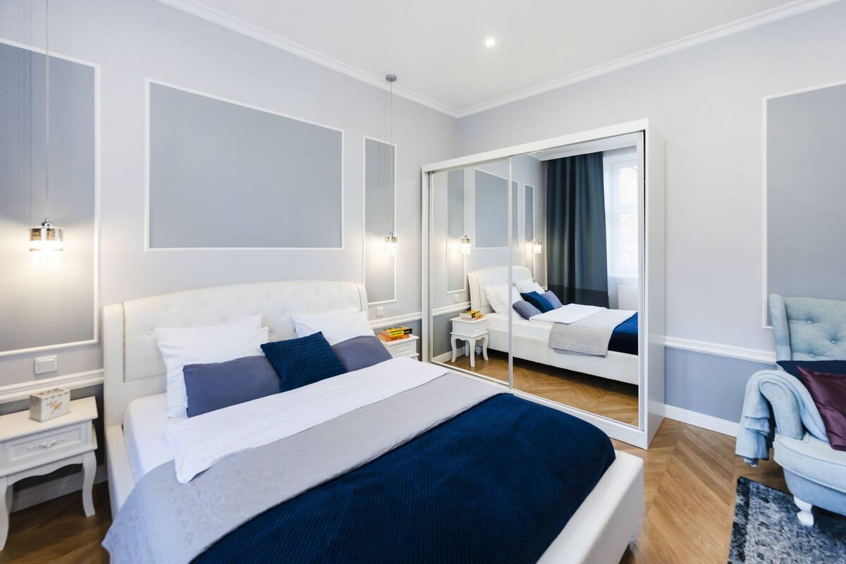 Una habitación de hotel moderna con una cama grande, un área de descanso y un espejo que refleja la habitación.