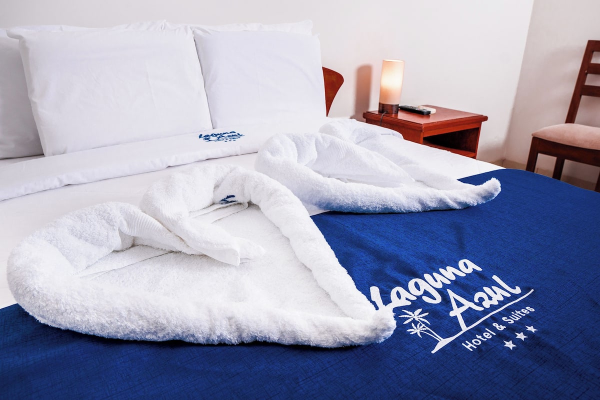 Una cama de hotel con una manta azul y una bata blanca.