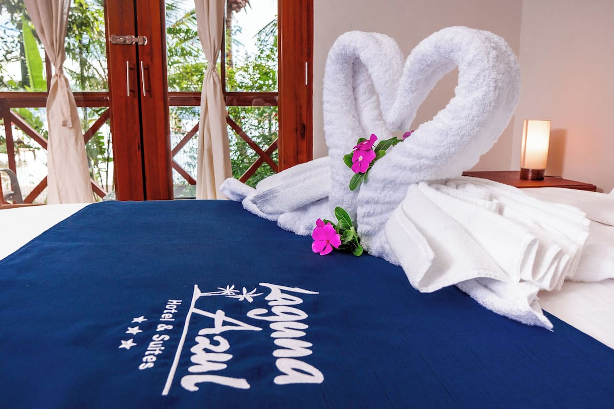 Una cama con un edredón azul y una toalla con forma de conejo y una flor rosa.