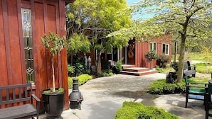 A wooden building with a covered porch, potted plants, and a bench. - Matai Huka Boutique Accommodation (Paraparaumu)